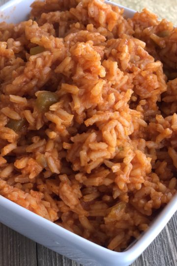 Mexican Rice in a white dish with a serving spoon