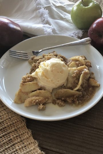 the BEST Apple crisp on a plate with a fork and apples in the background