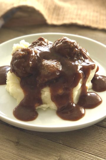 A plate of mashed potatoes with meatballs and brown gravy