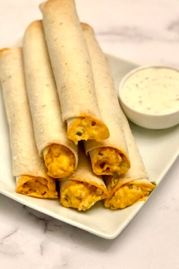 a plate of buffalo chicken ranch rollups stacked on top of each other with a side of ranch dressing next to them for dipping