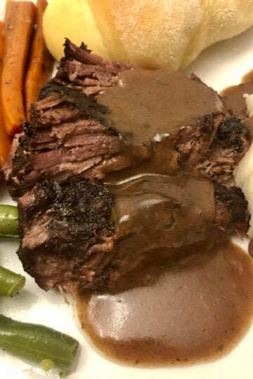 Pot roast with gravy and green beans and carrots on a plate
