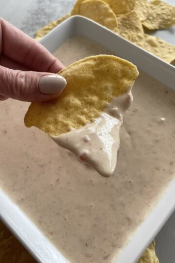 White queso dip eaten with tortilla a chips being dipped in the dip