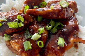 Plate of firecracker chicken with green onions served over rice