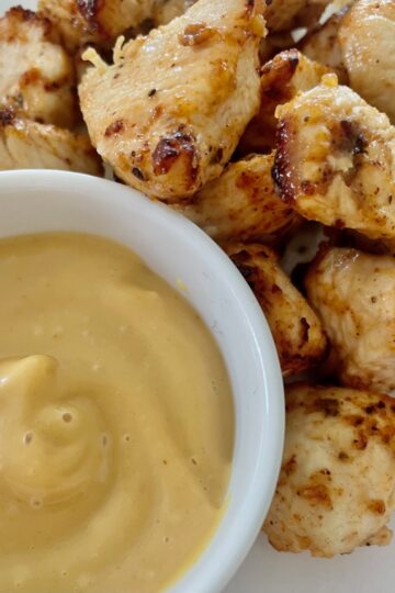 A small dish of Chik-fil-a sauce with air fryer grilled chicken bites next to it.