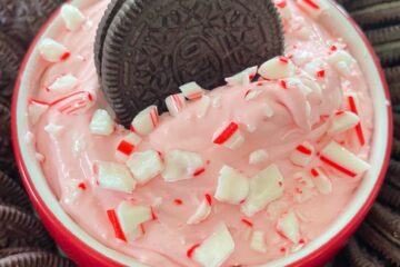 An OREO cookie dipped in dish of peppermint dip.