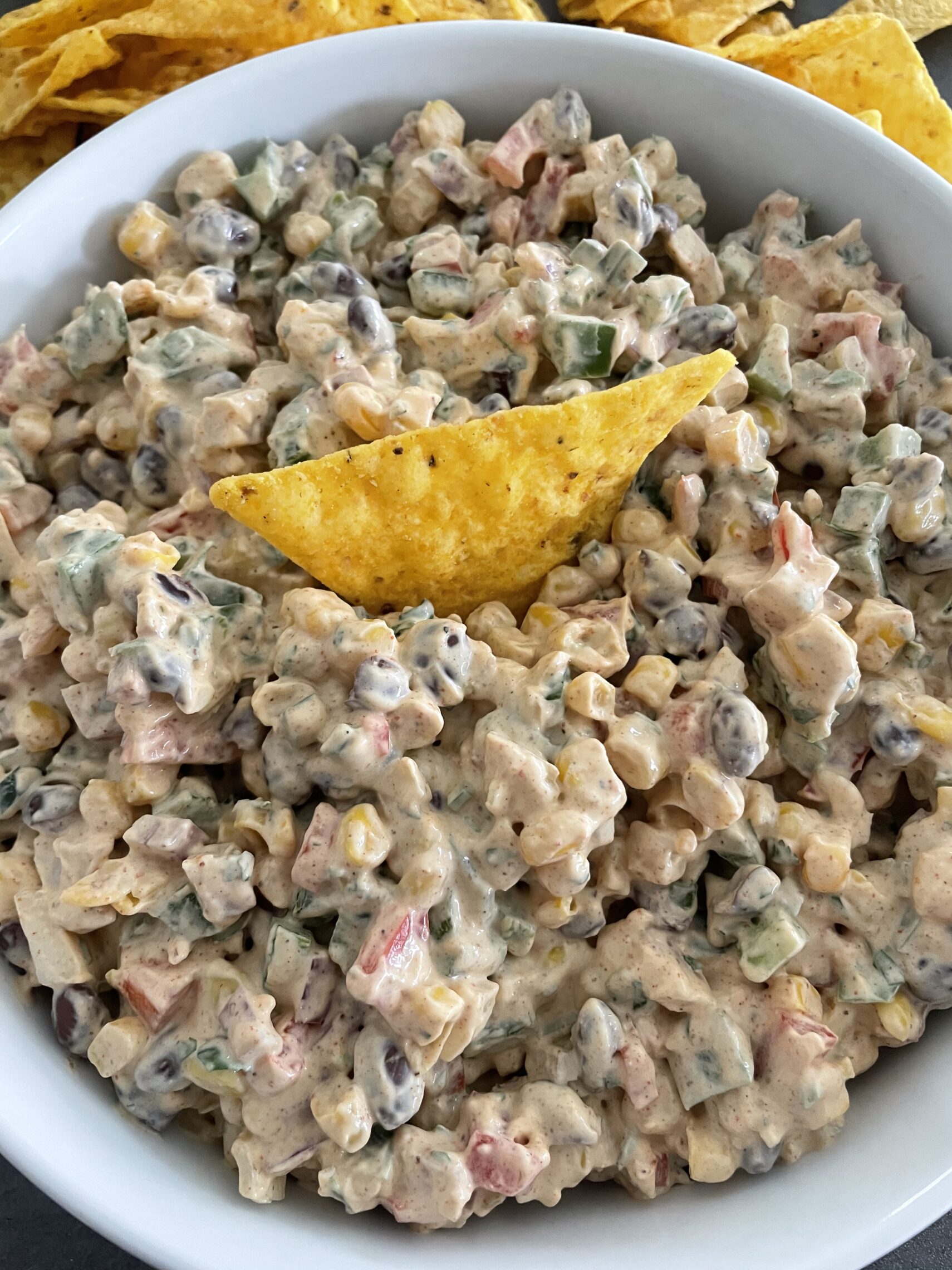 A bowl of Creamy Cowboy Caviar Dip with a tortilla chip dipped into the dip.